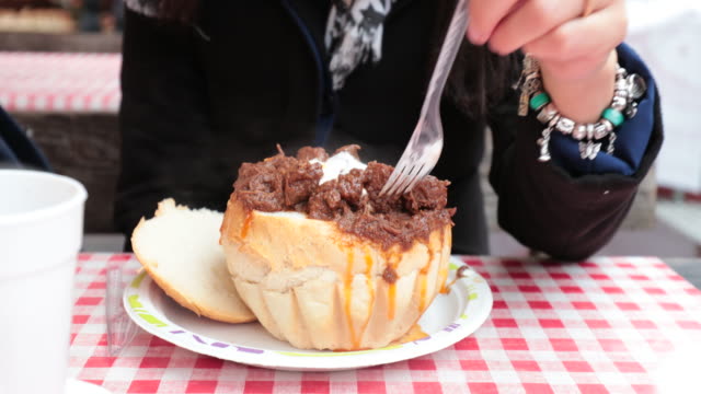 Tourist-girl-eating-a-Goulash-in-a-bread-bowl-at-christmas-annual-market-in-Budapest.-Tourist-woman-tasting-and-enjoying-traditional-hungarian-cuisine-in-4K