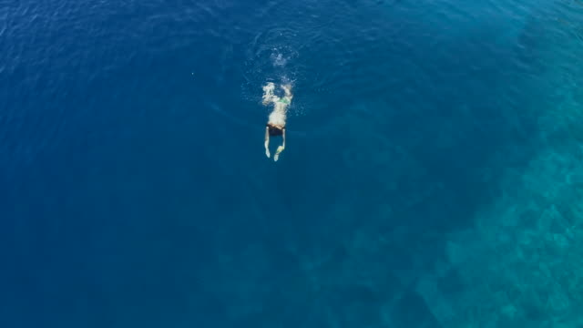 Aerial-Footage-of-a-Girl-Swimming-In-Blue-Sea