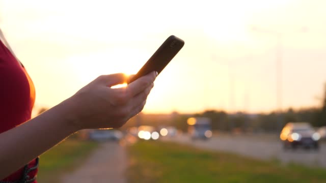 Mano-femenina-con-smartphone-contra-conducir-coches-en-el-camino