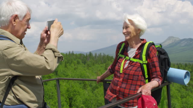 Excursionistas-seniors-fotografiando-en-la-parte-superior-de-la-montaña