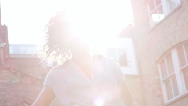Modisch-junge-schwarze-Frau-im-blauen-Kleid,-die-im-Sonnenlicht-auf-der-Straße,-Hintergrundbeleuchtung,-niedrigen-Winkel-stehen