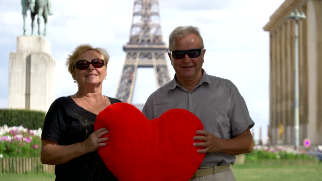 Senior-pareja-de-enamorados-con-corazón-enorme-frente-a-Eiffel-torre-en-4-k-lenta-60fps