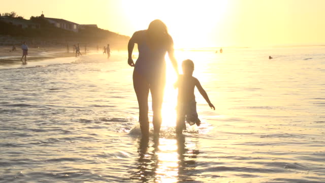 Mother-and-child-playing-on-beach-in-silhouette-at-sunset,Cape-Town