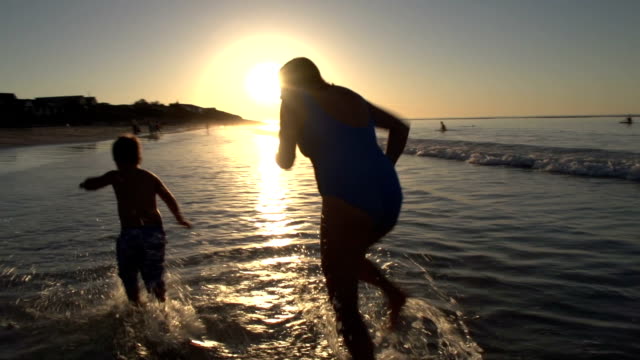 Mutter-und-Kind-spielen-am-Strand-auf-silhouette-bei-Sonnenuntergang,-Cape-Town