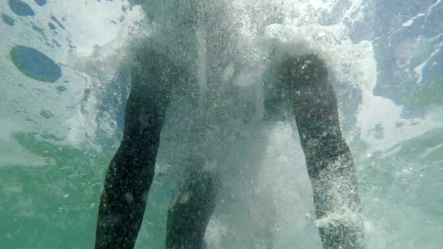 SLOW-MOTION-CLOSE-UP:-Happy-young-surfer-doing-duck-dive