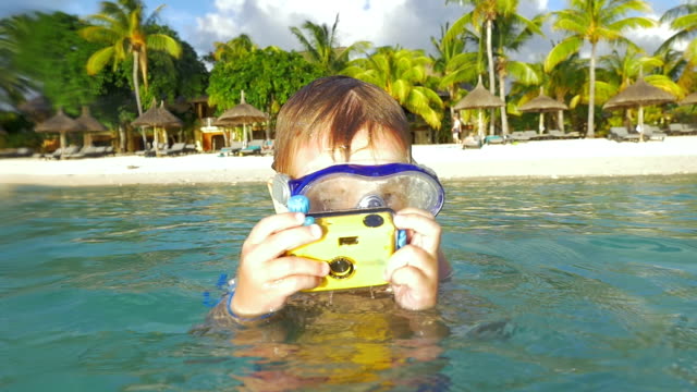Niño-bañándose-en-el-mar-y-tomar-fotos-con-cámara-resistente-al-agua
