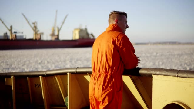 Young-man-in-orange-uniform-traveling-on-board-of-the-ship-in-winter.
