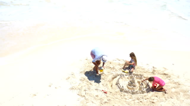 Blick-von-oben-auf-Vater-und-Töchter-machen-Sandburg-am-tropischen-Strand
