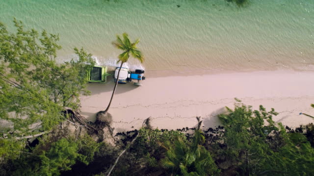 Aerial-video-of-Punta-Cana-beach.-Beach-Sand-Cleaning-Truck,-running-man-and-palm-trees.