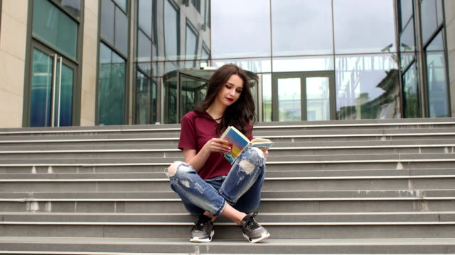 Junges-Mädchen-in-einem-Buch-sitzen-auf-Stufen-bei-city