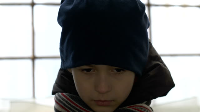 muchacho-de-refugiados-demacrado-retrato-está-solo-cerca-de-una-ventana-rota,-mirando-a-la-cámara