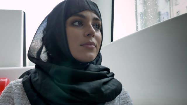 Junge-muslimische-Frau-Hijab-ist-gerade-im-Fenster-im-Bus,-Regenwetter,-Transportkonzept,-städtebauliche-Konzept