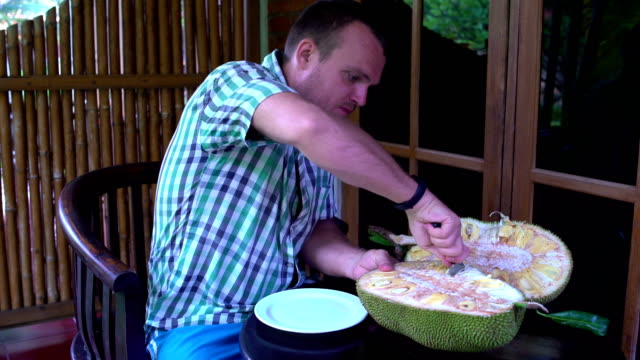 A-man-cuts-a-jackfruit-with-a-knife-on-the-terrace
