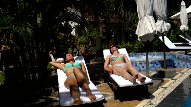 Frauen-in-Badeanzügen-auf-einem-Liegestuhl-Sonnen.-Frau-trinkt-einen-cocktail