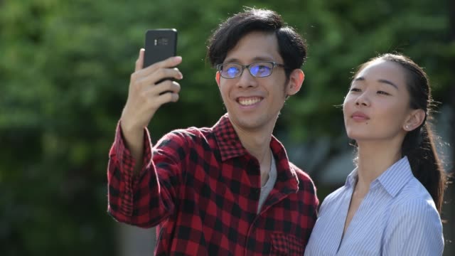 Video-joven-pareja-asiática-llamada-juntos-al-aire-libre