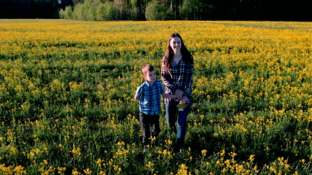 Mutter-und-Sohn-gehen-auf-dem-Gebiet-der-gelben-Blüten.