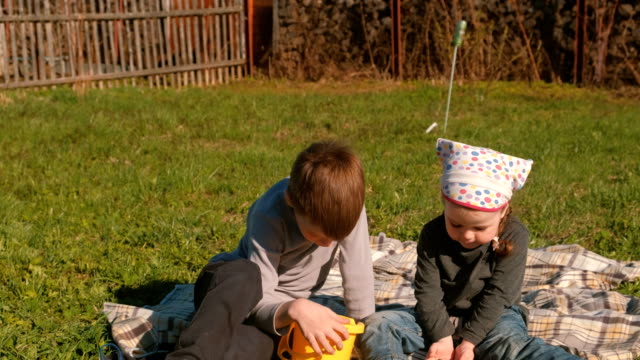 Bruder-und-Schwester-anzeigen-Regenwürmer-sitzen-auf-dem-Rasen-im-Garten-des-Hauses.