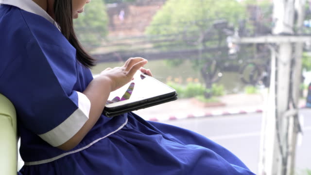 Asiatische-kleine-Schülerin-spielen-schreiben-auf-Smartphones-im-café