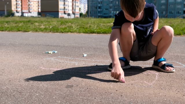 Boy-draws-with-blue-chalk-on-the-asphalt.-Close-up-hands.