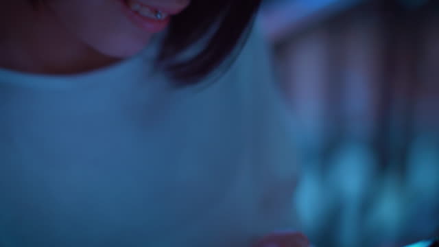 Porträt-von-die-attraktive-Japanerin-mit-Piercing-und-tragen-legere-Kleidung-verwendet,-Arten-auf-einem-Smartphone.-Im-Hintergrund-Plakate-Großstadt-Werbung-Lichter-leuchten-in-der-Nacht.