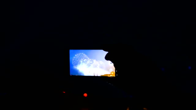 Man-shoots-fireworks-on-the-phone-and-watches-salute-through-the-smartphone-screen