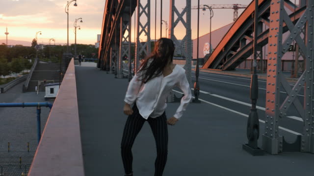 Junge-Frau-tanzt-auf-der-Stadtbrücke-und-goldenen-Sonnenuntergang-Panorama