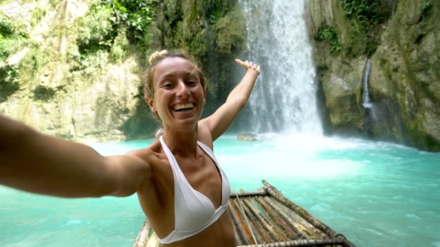 Junge-Frau-unter-Selfie-Porträt-mit-einem-wunderschönen-Wasserfall-auf-der-Insel-Cebu-in-den-Philippinen.-Die-Leute-reisen-Natur-Selfie-Konzept.-Eine-Person,-die-nur-genießen,-Natur-und-Ruhe-in-einem-friedlichen-Umfeld---4K-video