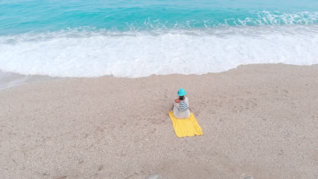 Mujer-sentada-en-la-playa-y-viendo-el-mar-ondulado