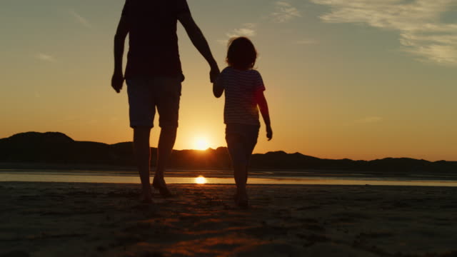 Silhouette-Of-Father-And-Son-Walking-Together-At-Beach