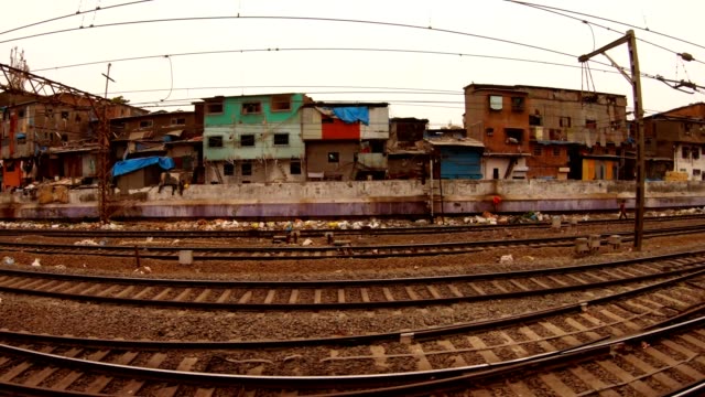 tren-local-con-pasajeros-revoque-en-la-vista-frontal-de-las-líneas-ferroviarias-y-el-distrito-pobre-de-Mumbai