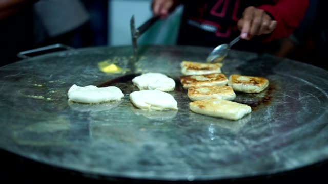 Vendedor-de-comida-callejera-haciendo-Roti-Canai-en-una-sartén