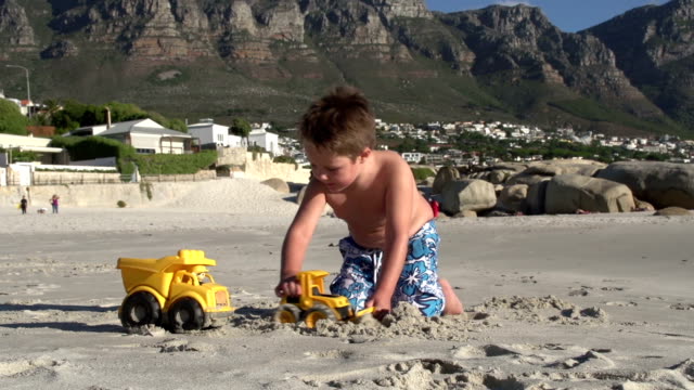 Young-boy-playing-with-toys-on-beach,-Cape-Town,South-Africa