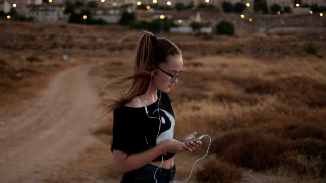 Teenager-Mädchen-mit-eyeglasses-hören-Sie-die-Musik-auf-den-Sonnenuntergang