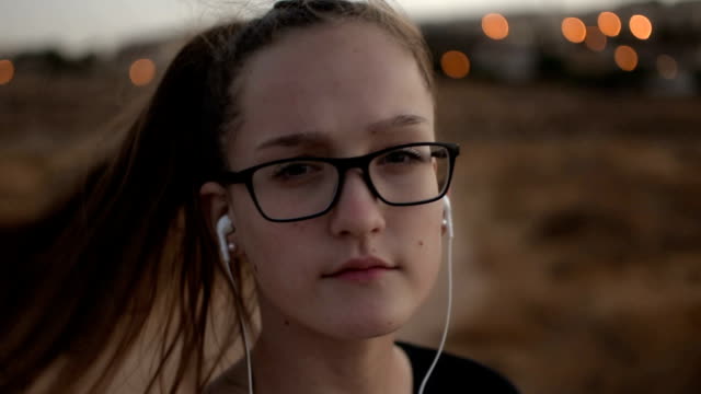Teenager-Mädchen-mit-eyeglasses-hören-Sie-die-Musik-auf-den-Sonnenuntergang