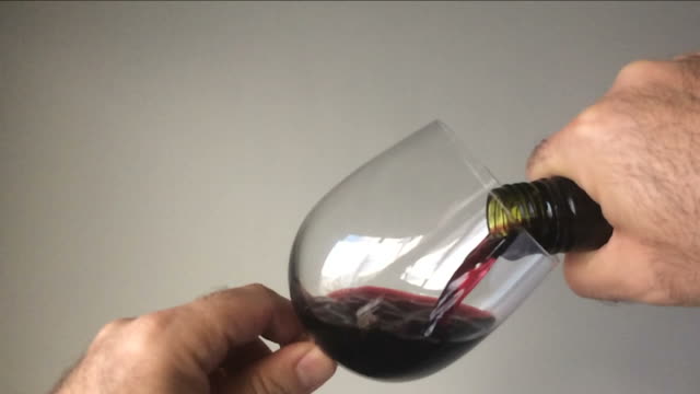 Slow-Motion-eines-Mannes-Rotwein-aus-der-Flasche-in-ein-Glas-Wein-in-Strömen