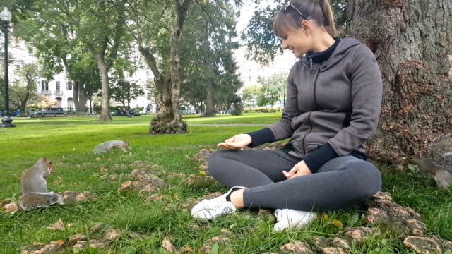 CLOSE-UP:-Young-woman-giving-food-to-squirrels-in-Boston-Common-local-park,-USA