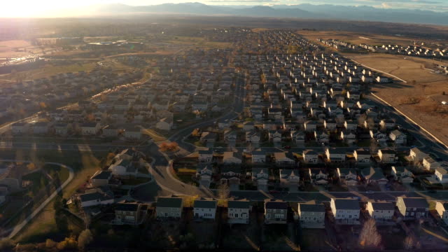 AERIAL:-Big-suburban-town-with-row-houses-surrounded-by-mountains-at-sunrise