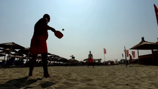 Vater-und-Sohn-Silhouetten-Tennis-spielen-gemeinsam-am-Strand