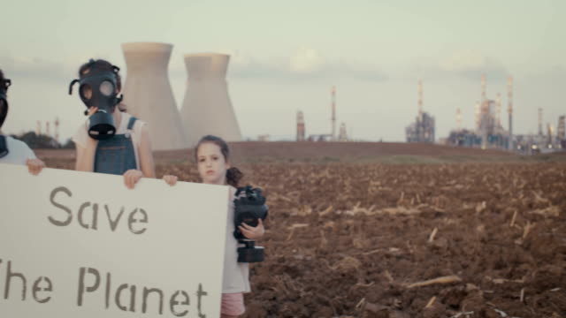 Save-the-plant.-Young-kids-holding-signs-near-a-refinery-with-gas-masks