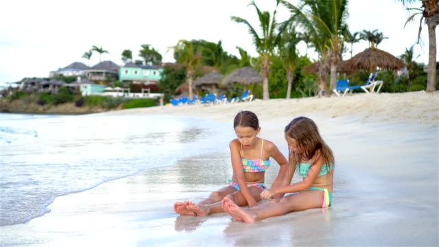 Entzückende-kleine-Mädchen-spielen-mit-Sand-am-Strand