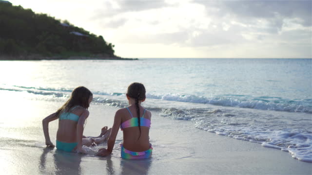Entzückende-kleine-Mädchen-spielen-mit-Sand-am-Strand