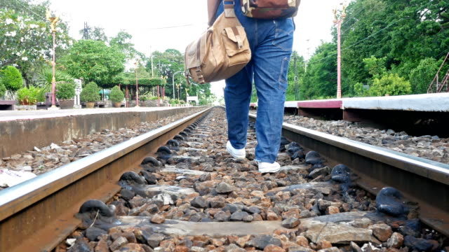 Women-wearing-jeans-carrying-luggage-on-a-railroad-track.She-stumble-but-still-walks-forward.Conception,-travel,--struggle-for-hard-work