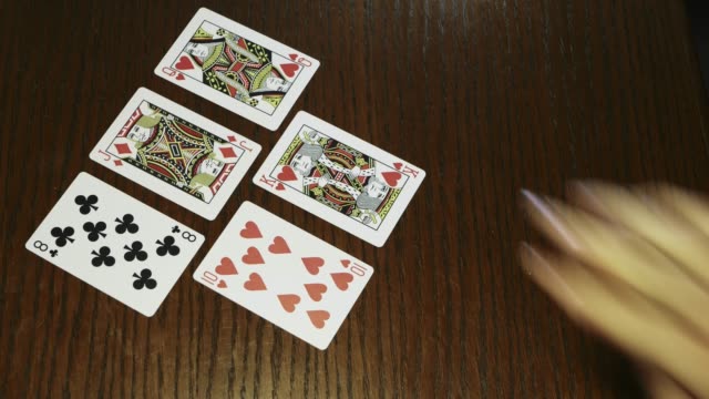 Hände-halten-Stapel-Spielkarten-auf-Holztisch