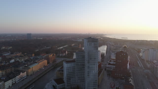 Vista-aérea-del-horizonte-de-paisaje-urbano-de-Malmö-al-atardecer.-Tiro-de-Drone-volando-sobre-la-ciudad-y-la-calle-y-hacia-atrás-del-moderno-rascacielos-edificio-centro