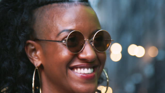 Fashionable-young-black-woman-in-sunglasses-enjoying-the-view,-head-shot,-bokeh-lights-in-background