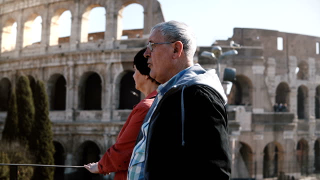 Feliz-activo-senior-caucásica-pareja-de-turistas-disfrutando-de-las-vistas-del-famoso-Coliseo-juntos-durante-el-viaje-a-Roma,-Italia.