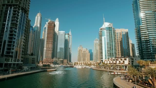 moving-panorama-from-bridge-in-Dubai-Marina-in-sunny-day,-reflection-from-water