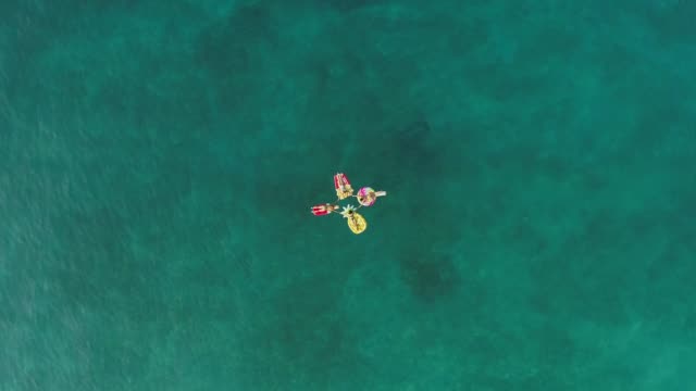 Luftaufnahme-der-Gruppe,-die-die-Hände-auf-aufblasbarer-Matratze-auf-der-Insel-Atokos-hält.