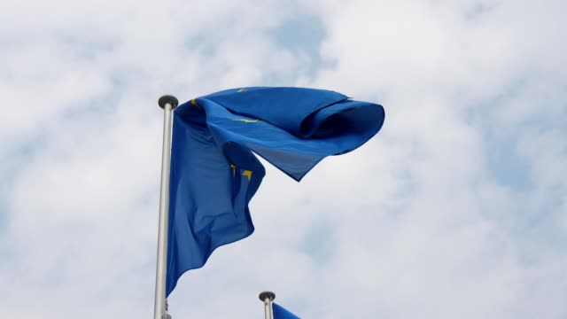Hermosa-vista-de-una-bandera-de-la-Unión-Europea-con-un-fondo-azul-y-un-círculo-de-estrellas-en-Bruselas-en-un-día-soleado-en-primavera-en-cámara-lenta.