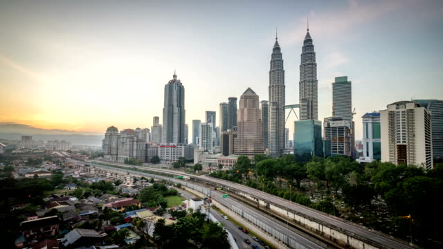 4k-footage-timelapse-of-beautiful-sunrise-at-Kuala-Lumpur-city-centre-from-a-rooftop-of-a-building,-with-city-skyline,-highway,-and-burst-sunlight.-Zoom-in-and-pan-left.